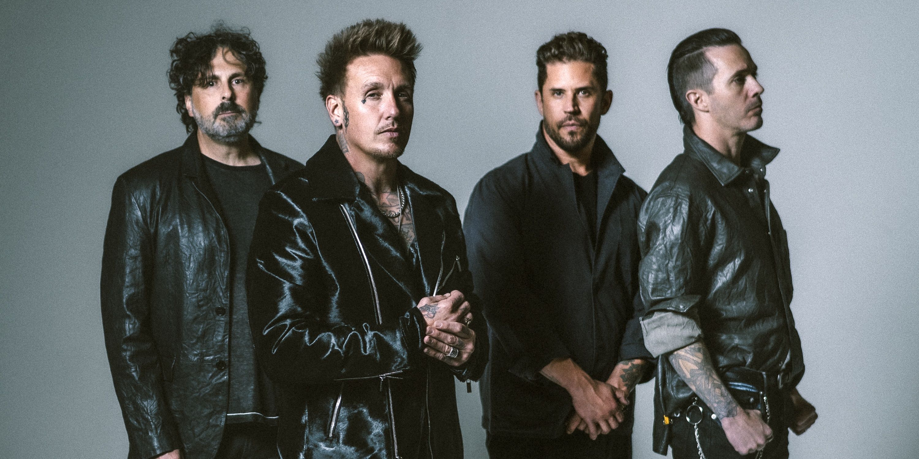 Papa Roach standing side by side with frontman Jacoby Shaddix slightly forward with clasped hands