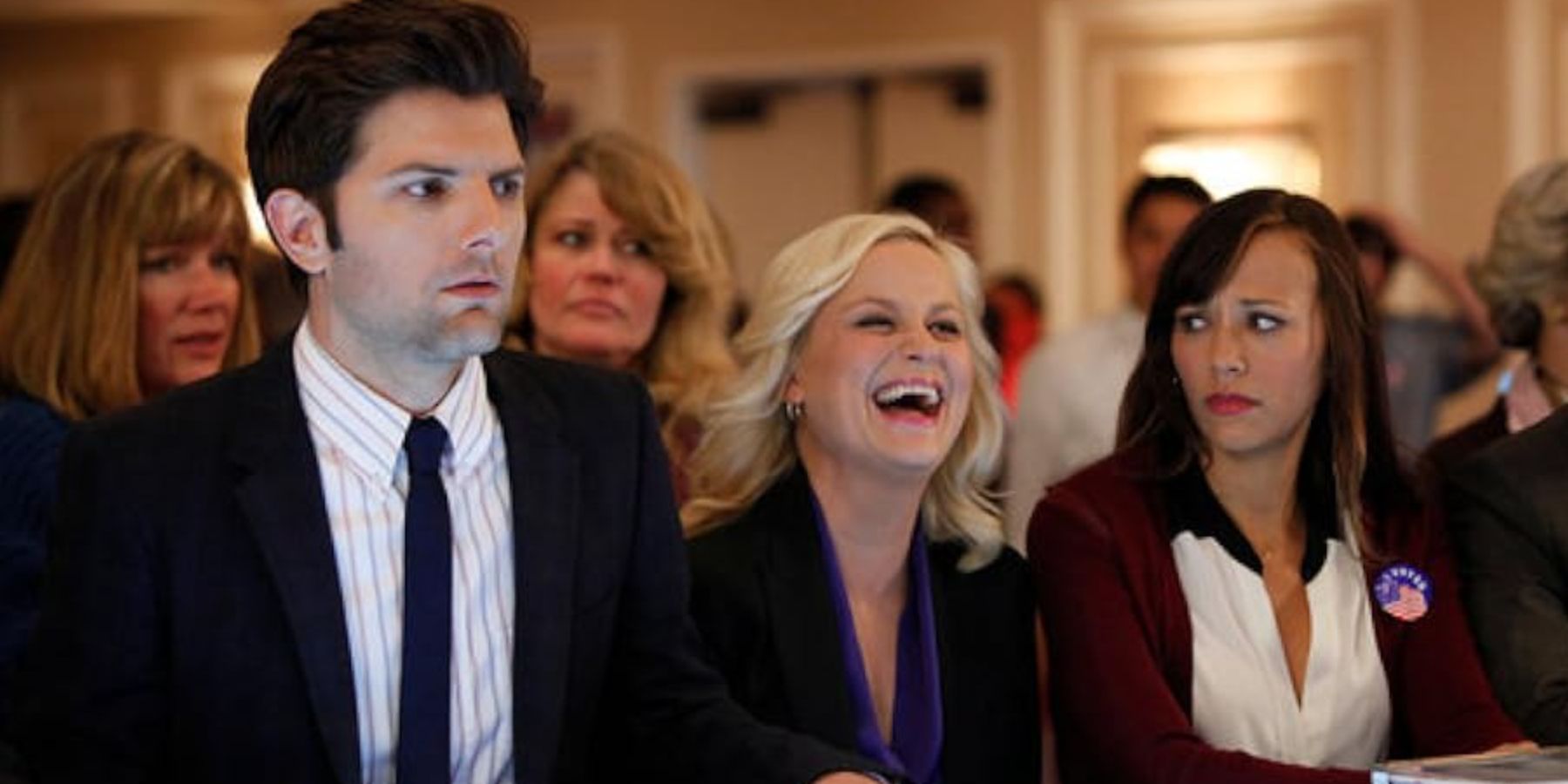 Leslie Knope (Amy Poehler) laughs while Ben (Adam Scott) and Ann (Rashida Jones) watch concerned in Parks and Recreation.