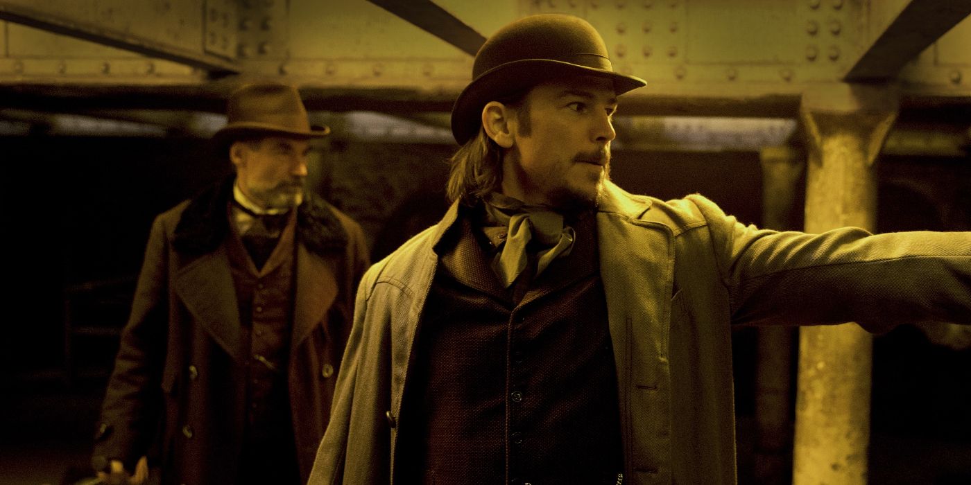 Ethan Chandler (Josh Hartnett) aiming his gun offscreen toward the right with Malcom Murray (Timothy Dalton) standing behind him on his left in Penny Dreadful