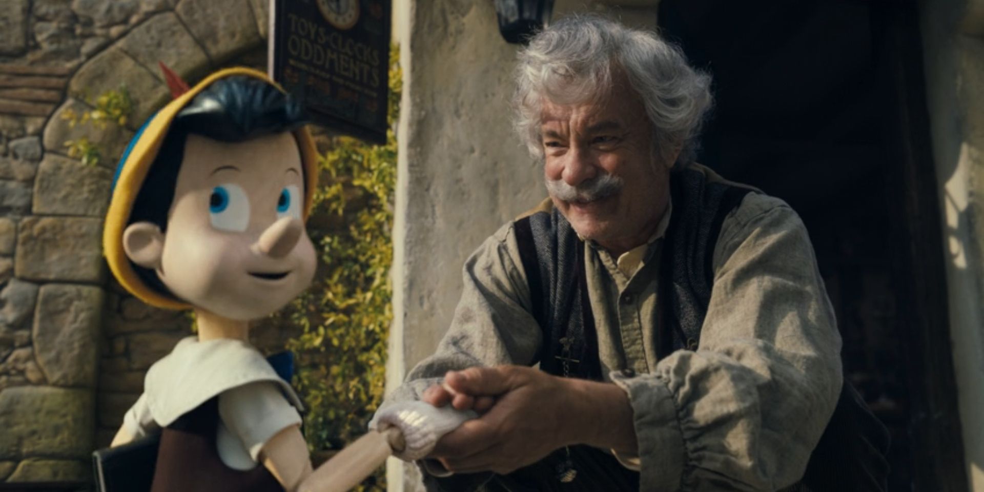 Pinocchio, voiced by Benjamin Evan Ainsworth, holds hands with Geppetto, played by Tom Hanks, in 'Pinocchio'.