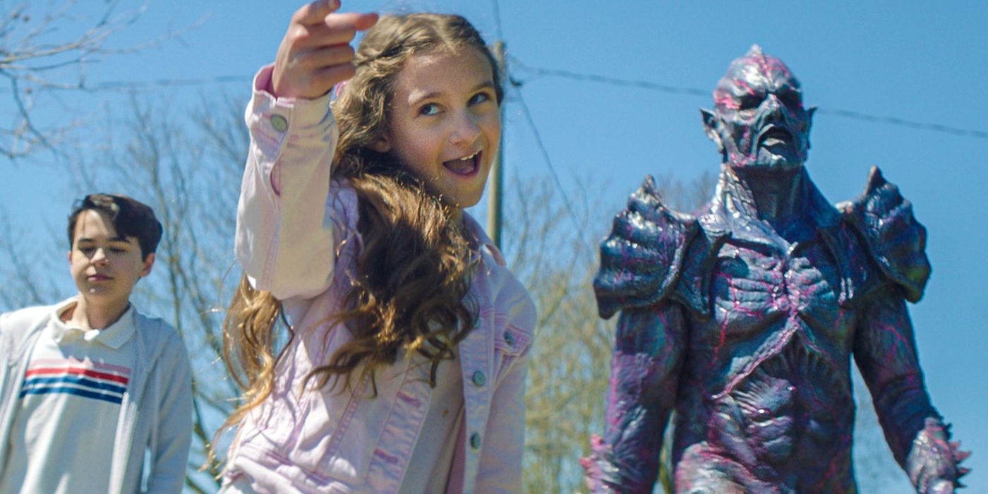 Brother and sister Mimi and Luke alongside Psycho Goreman, with Mimi pointing forward.