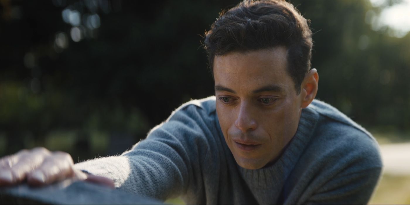 Rami Malek as Charlie Heller resting his hand on a gravestone in The Amateur.