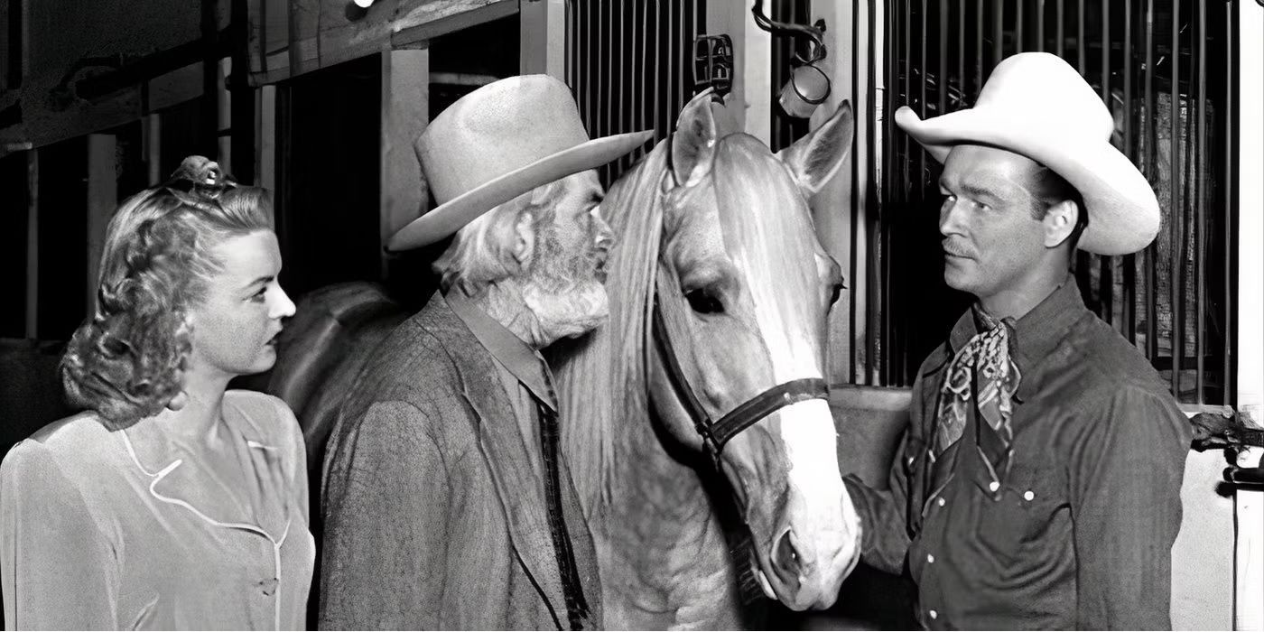 Roy Rogers stands next to his horse Trigger in a stable with two other people in My Pal Trigger. 