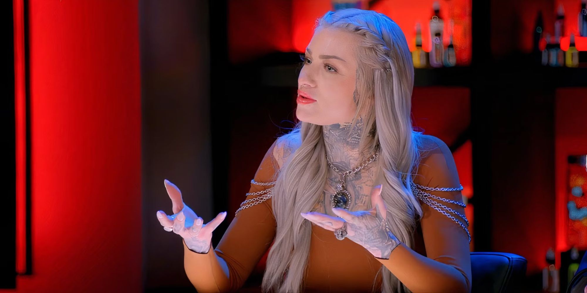 Judge Ryan Ashley Malarkey sits behind a table and talks to someone off camera in Ink Master Season 16.