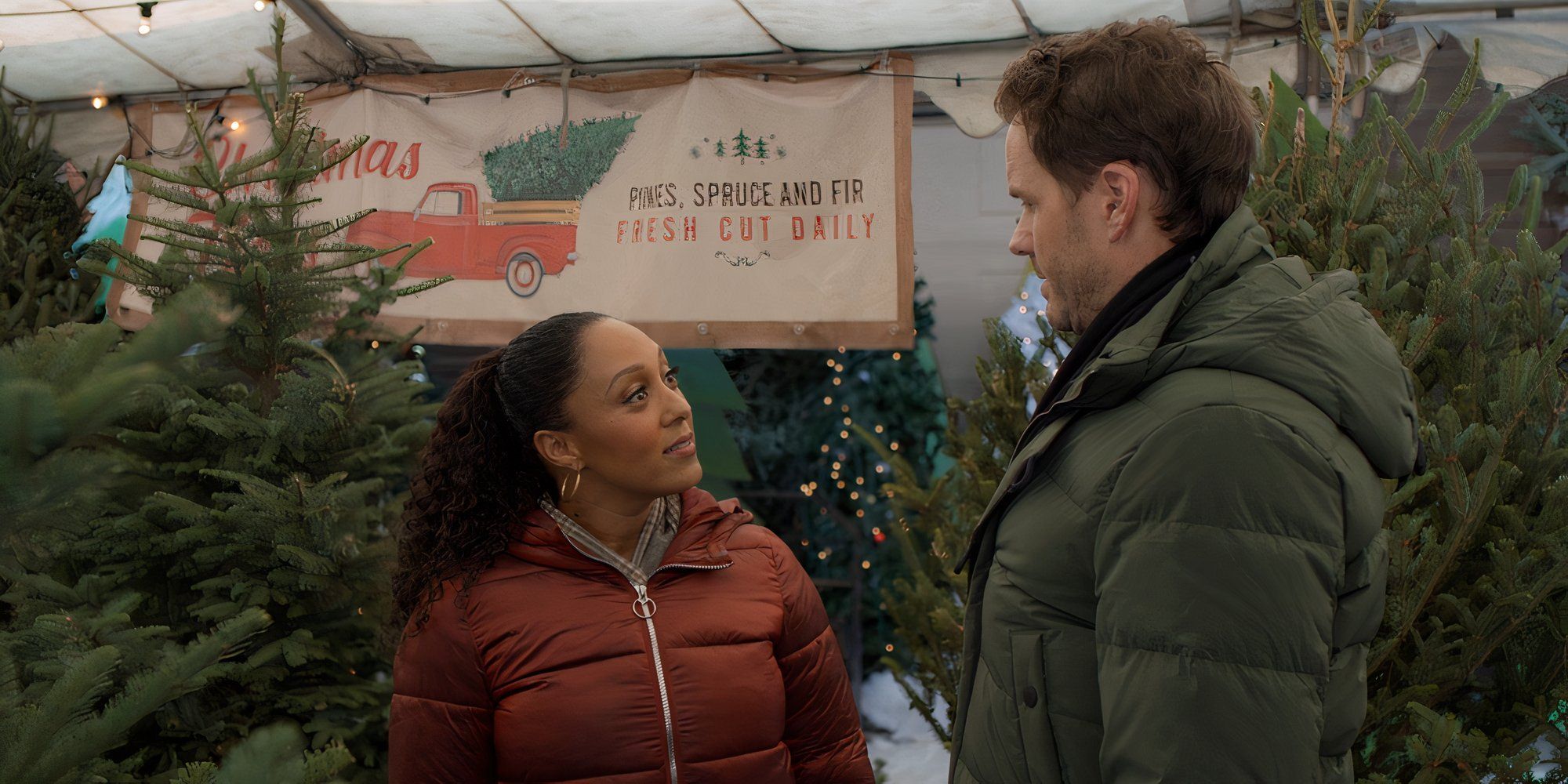 Tamera Mowry-Housley as Tanya looks at Paul Campbell as Ryan in a Christmas tree farm in Santa Stakeout.