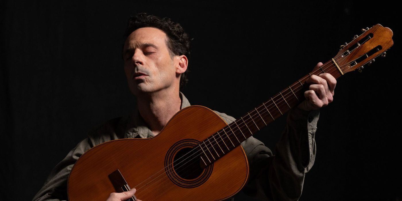 Scoot McNairy strumming a guitar as Woody Guthrie in A Complete Unknown.