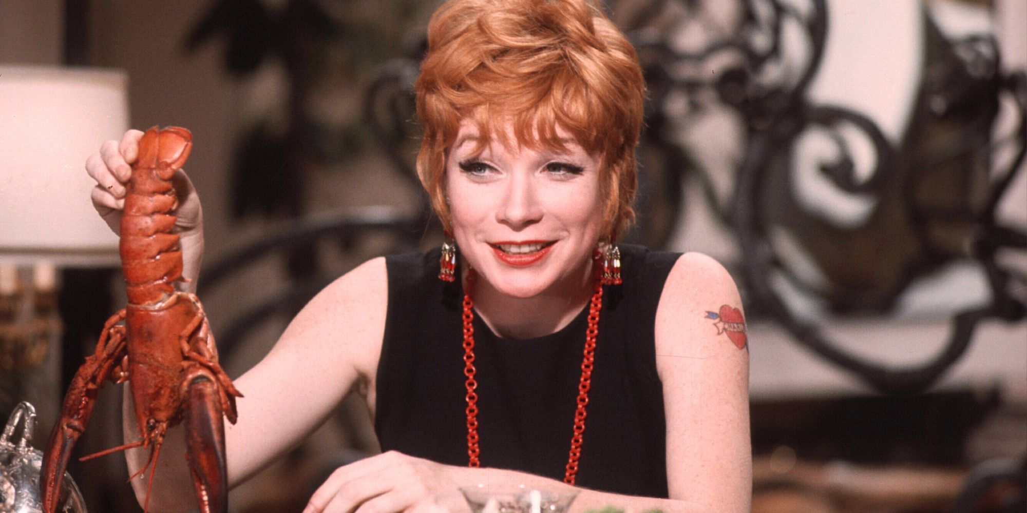 Shirley MacLaine sitting at a table holding up a lobster in Sweet Charity (1969)