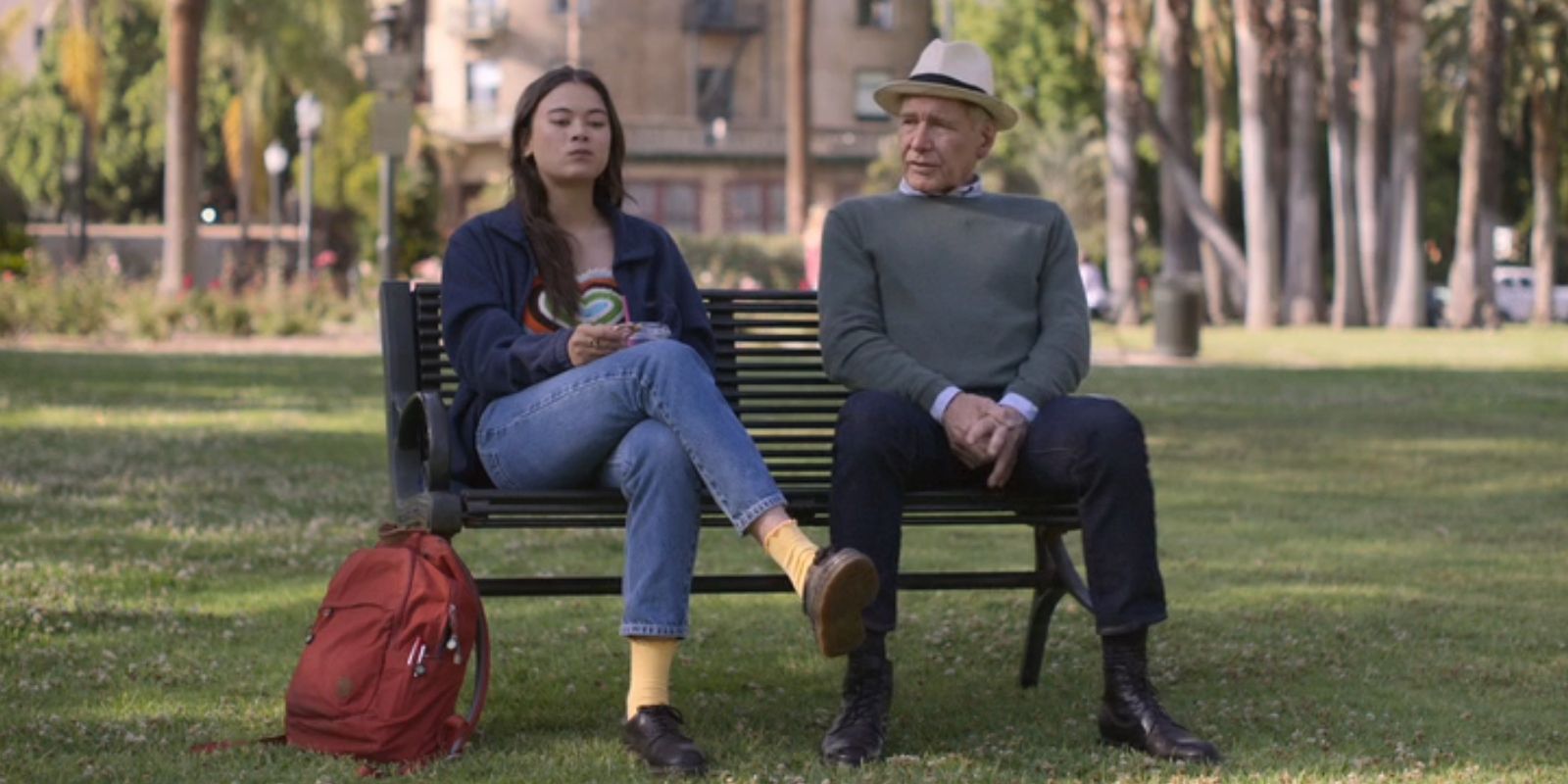 Alice, played by Lukita Maxwell, and Paul, played by Harrison Ford, sit side-by-side on a bench in 'Shrinking'.