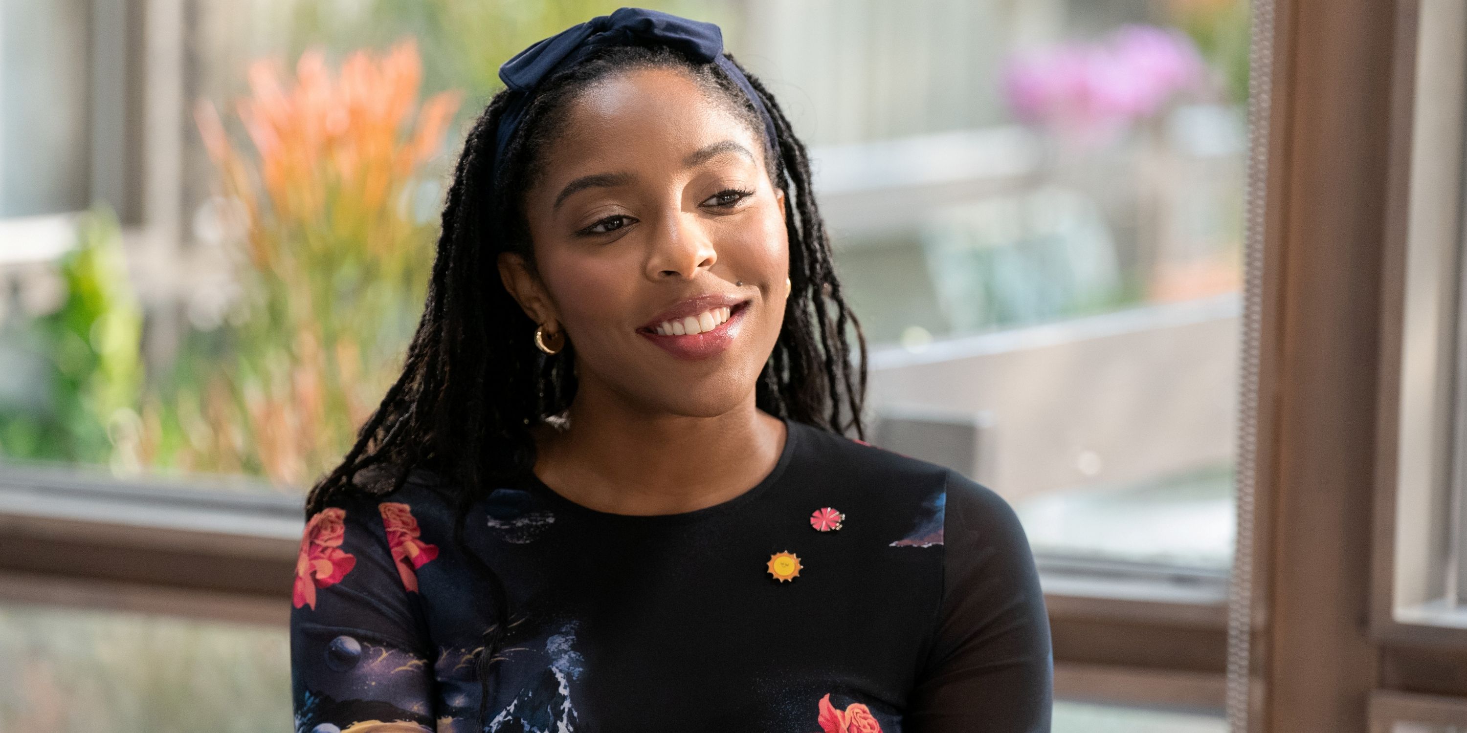 Jessica Williams as Gaby in a black print top sitting in her office in Season 2 of Shrinking