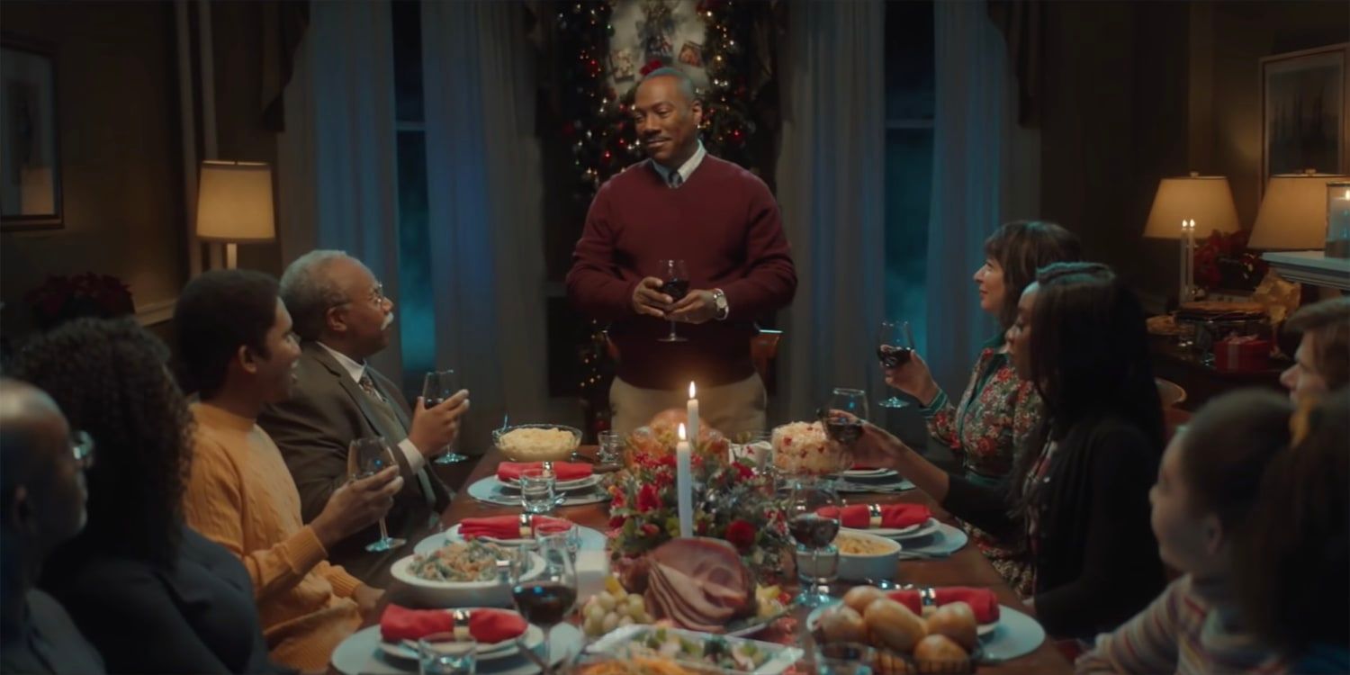 Eddie Murphy standing at the table of a family dinner in Saturday Night Live skit Home for the Holidays.