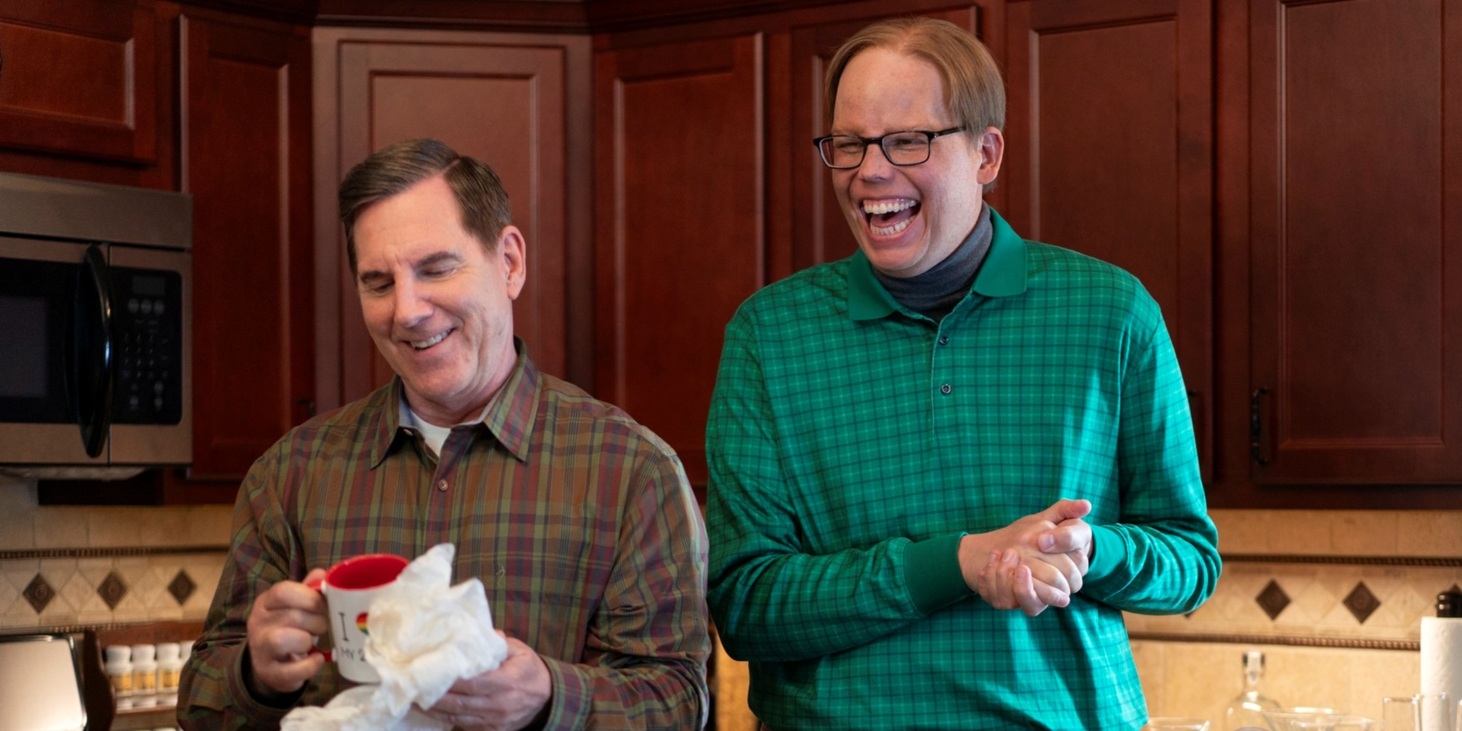 Jeff Hiller as Joel smiling with Tim Bagley as Brad holding a mug in Season 3 of Somebody Somewhere