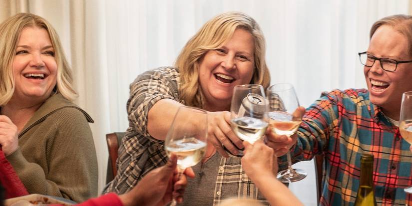 People sitting at a dinner table and cheering glasses of wine together in Somebody Somewhere Season 3.