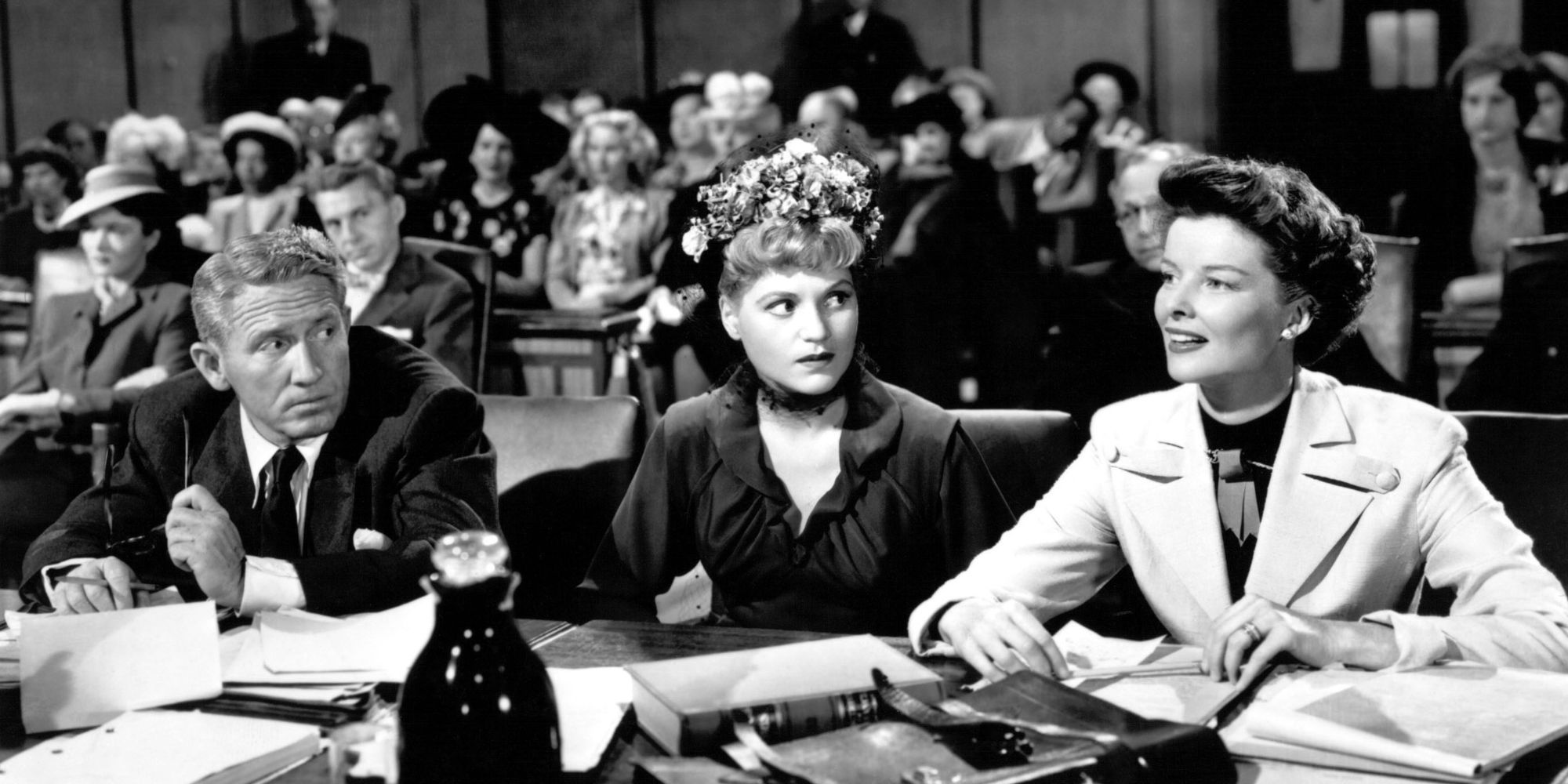 Spencer Tracy, Judy Holliday and Katharine Hepburn sitting next to each other at a table in a court room in Adam&rsquo;s Rib (1949)