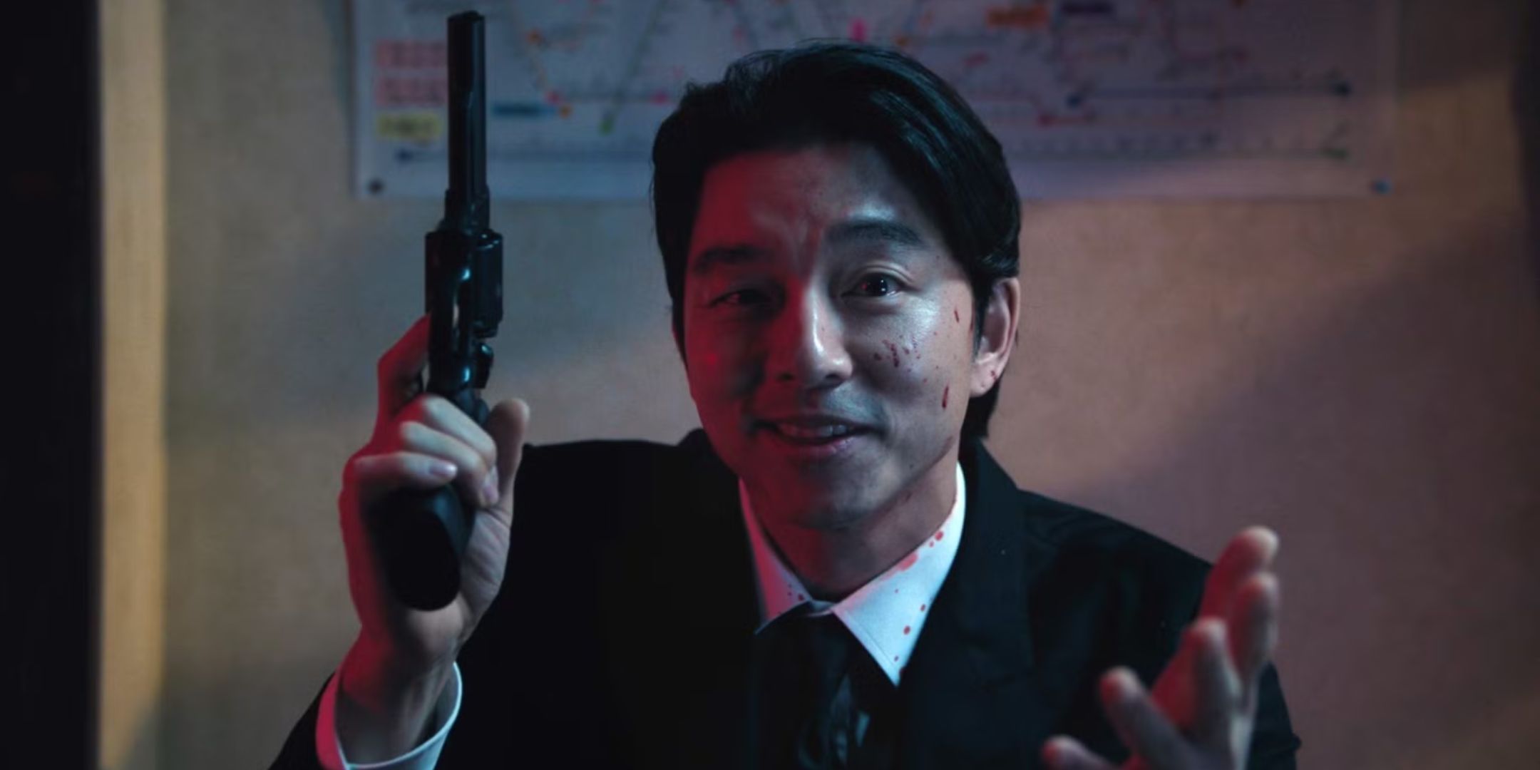 Gong Yoo as the Salesman playing russian roulette with a gun in Squid Game Season 2.