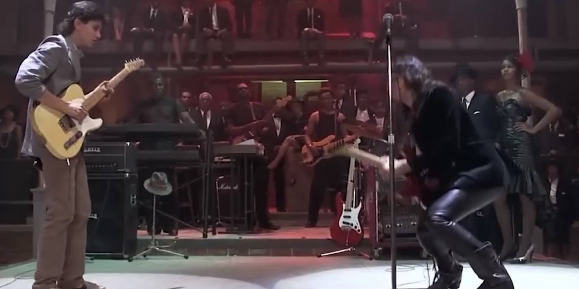 Dois homens jogando guitarras no palco na encruzilhada