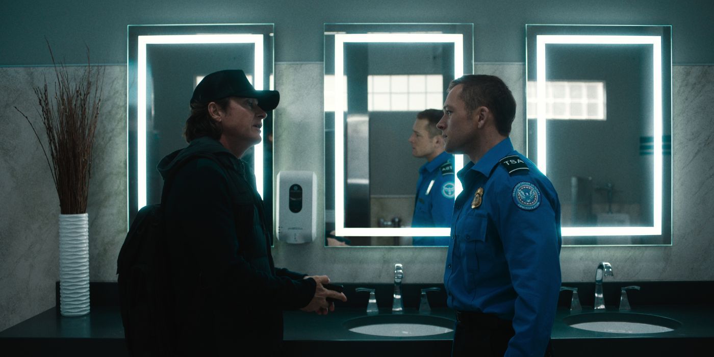 Jason Bateman and Taron Egerton facing each in an airport bathroom in Carry-On.