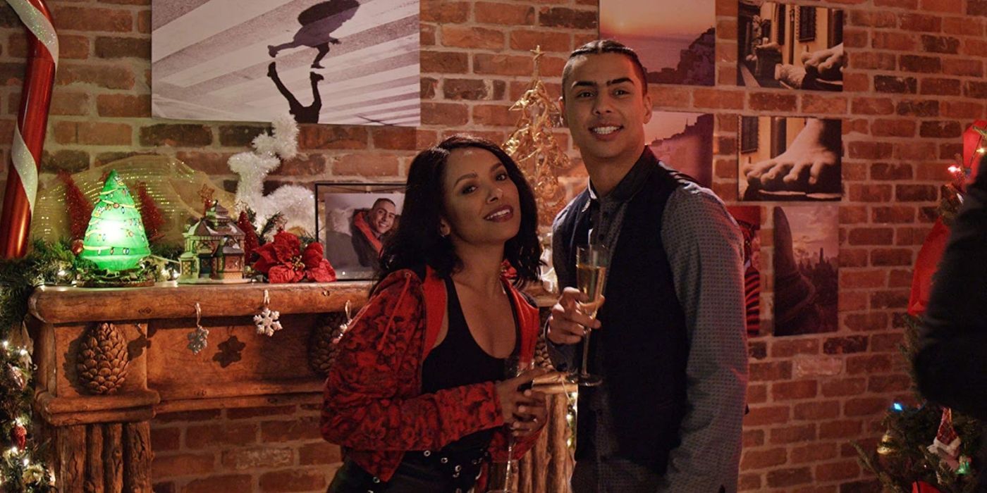 Kat Graham and Quincy Brown hold champagne glasses in front of a festive fireplace in The Holiday Calendar.