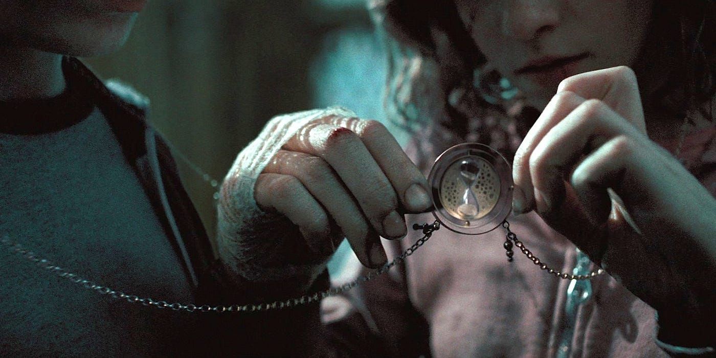 Hermione holds up a necklace with an hourglass time-turner charm on it in the Harry Potter series.