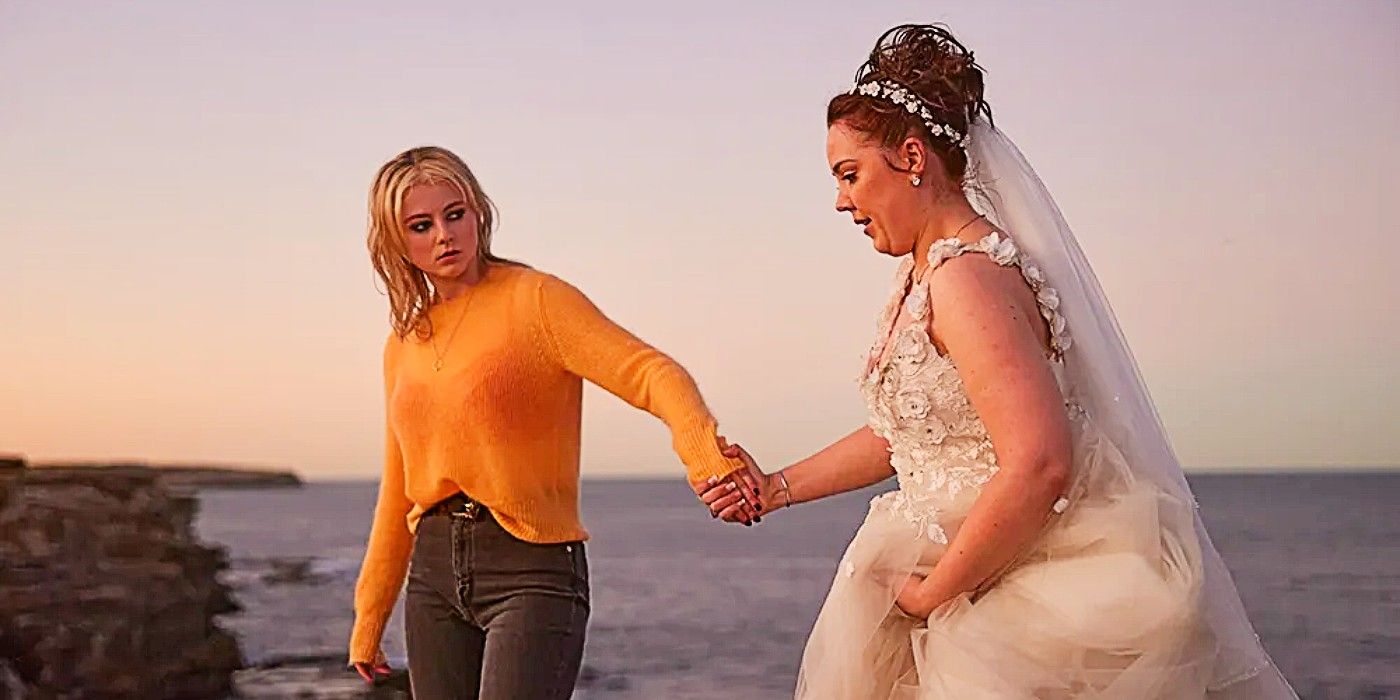Vivian holding Amy&rsquo;s hand (Amy wears a wedding dress) overlooking a cliff in Totally Completely Fine