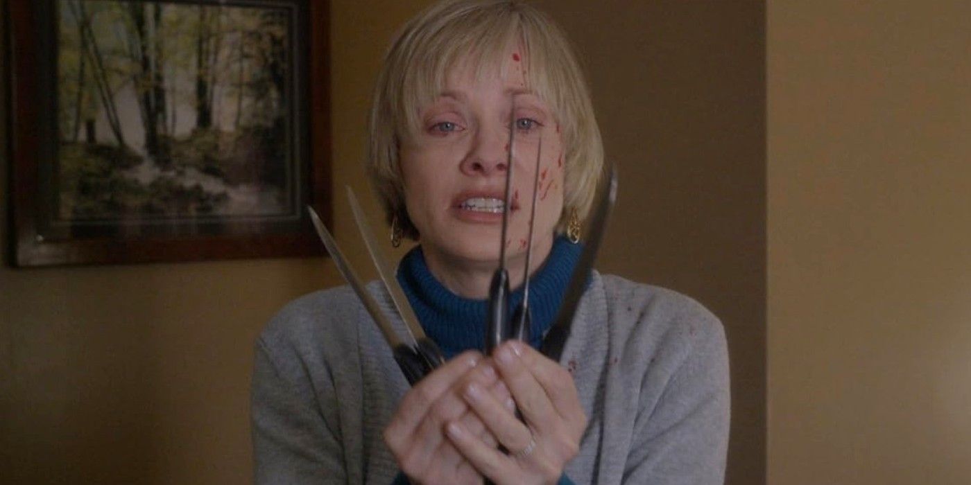 Barbara Crampton as Anne holding five steak knives in front of her blood-splattered face in "We Are Still Here"