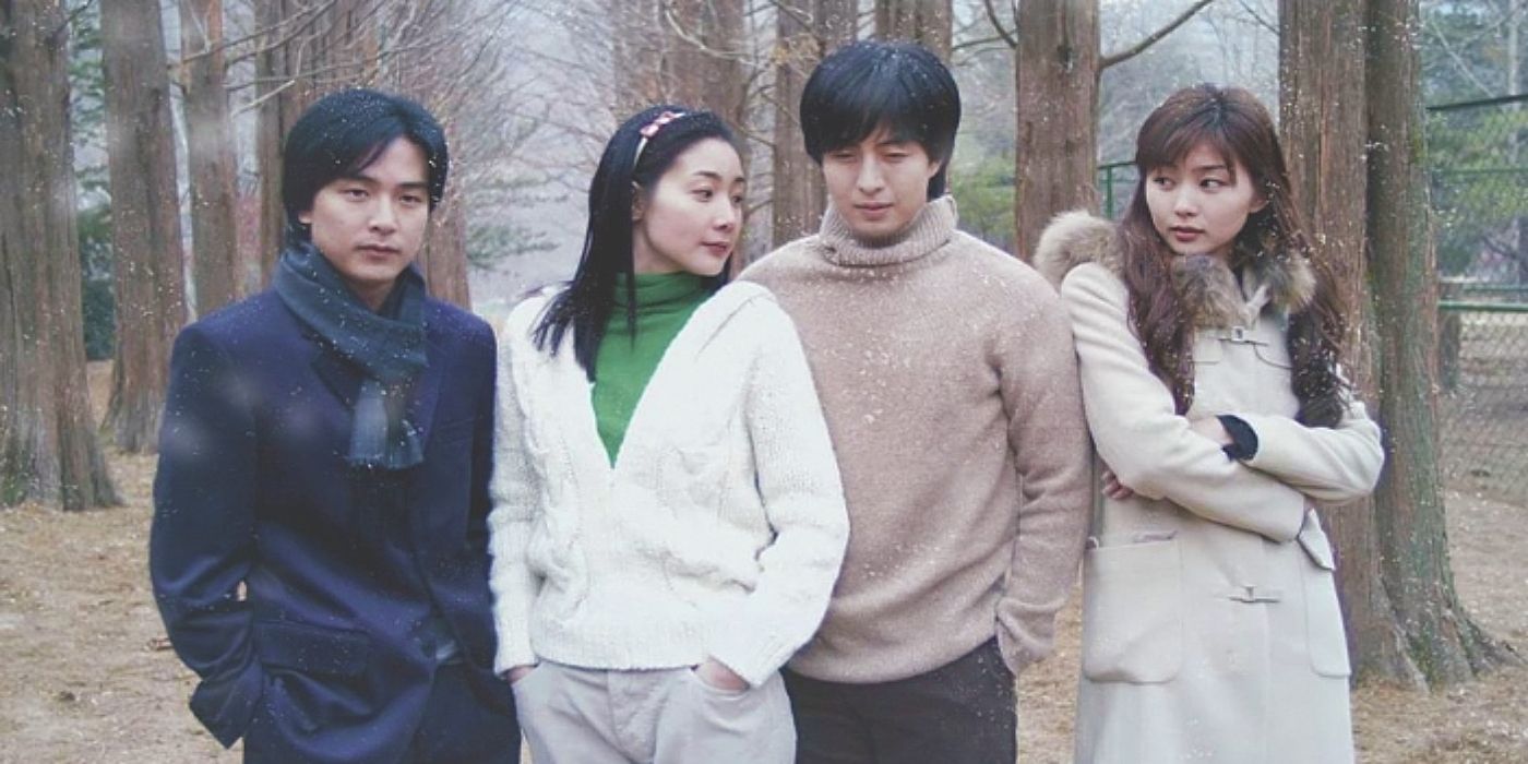 Characters from the K-drama Winter Sonata stand in front of barren trees wearing coats.