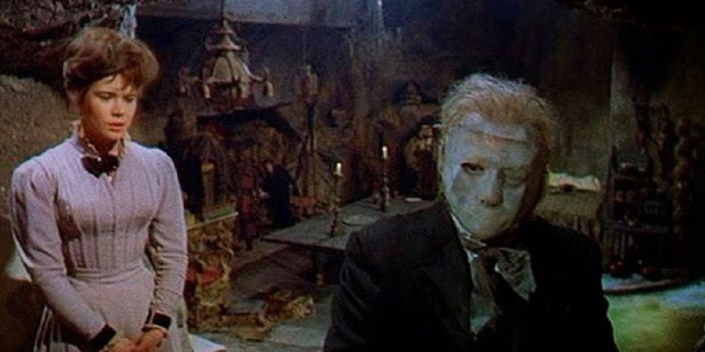 A woman is behind the Phantom who wears a full face mask in a cavernous lair in The Phantom of the Opera (1962).