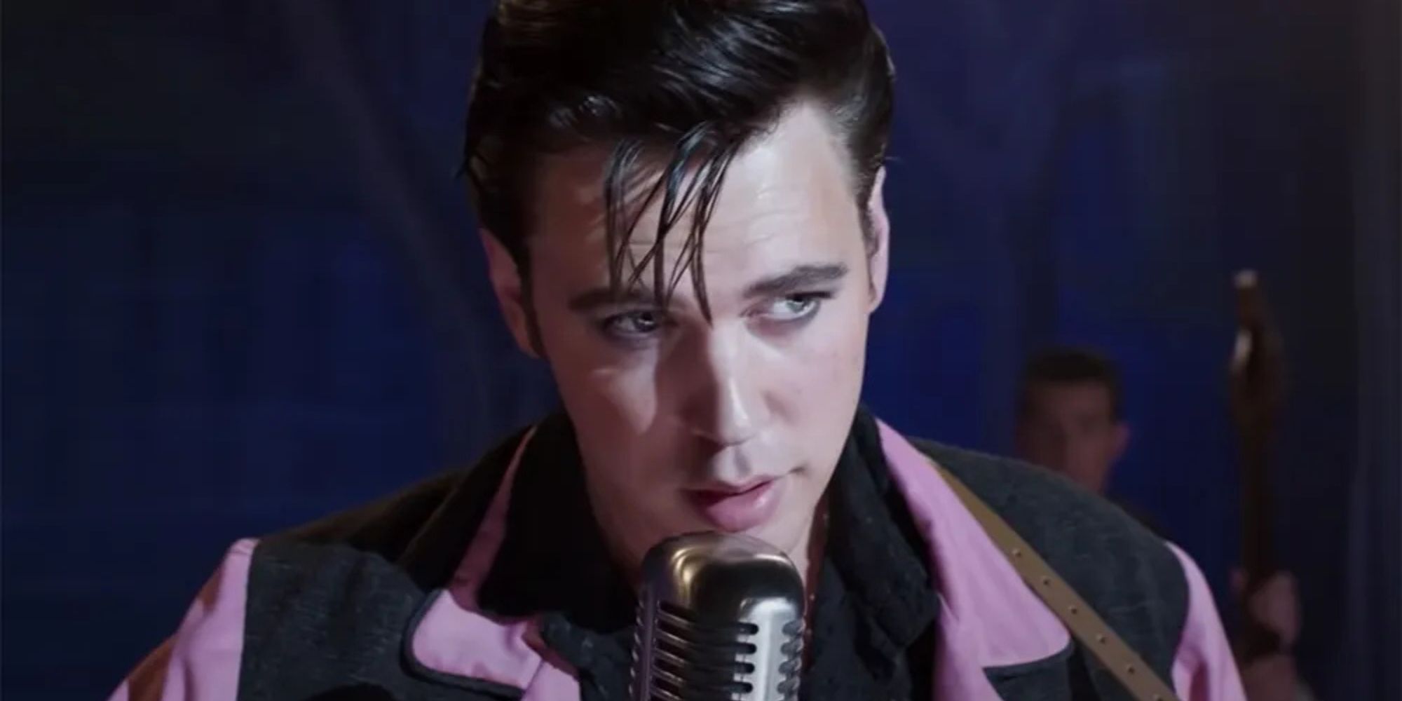 Austin Butler as Elvis Presley standing in front of a microphone in Elvis (2022)