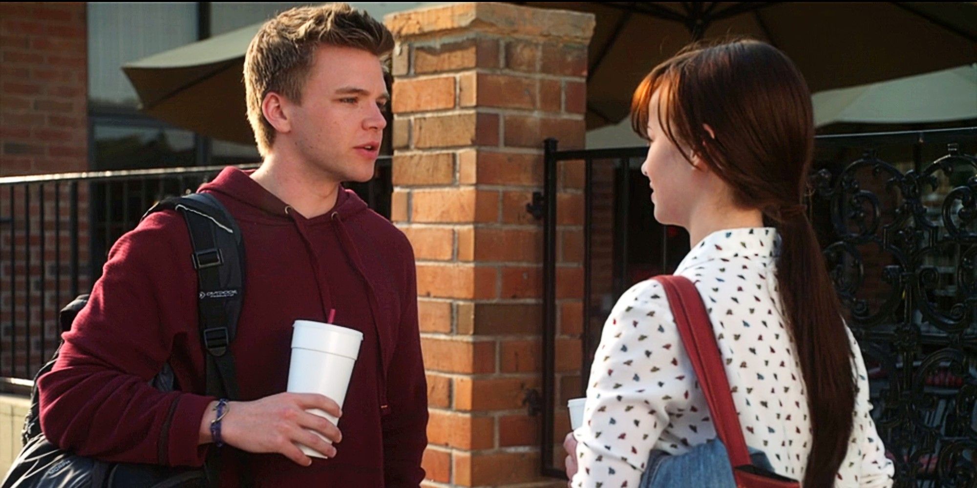 Jake Rosati and Jenna Hamilton talking to each other outside a school building in Awkward