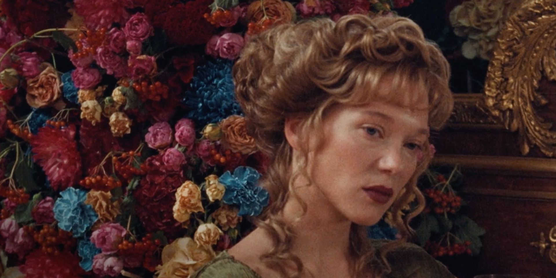 Lea Seydoux sits in front of a wall of flowers in 'The Beast'