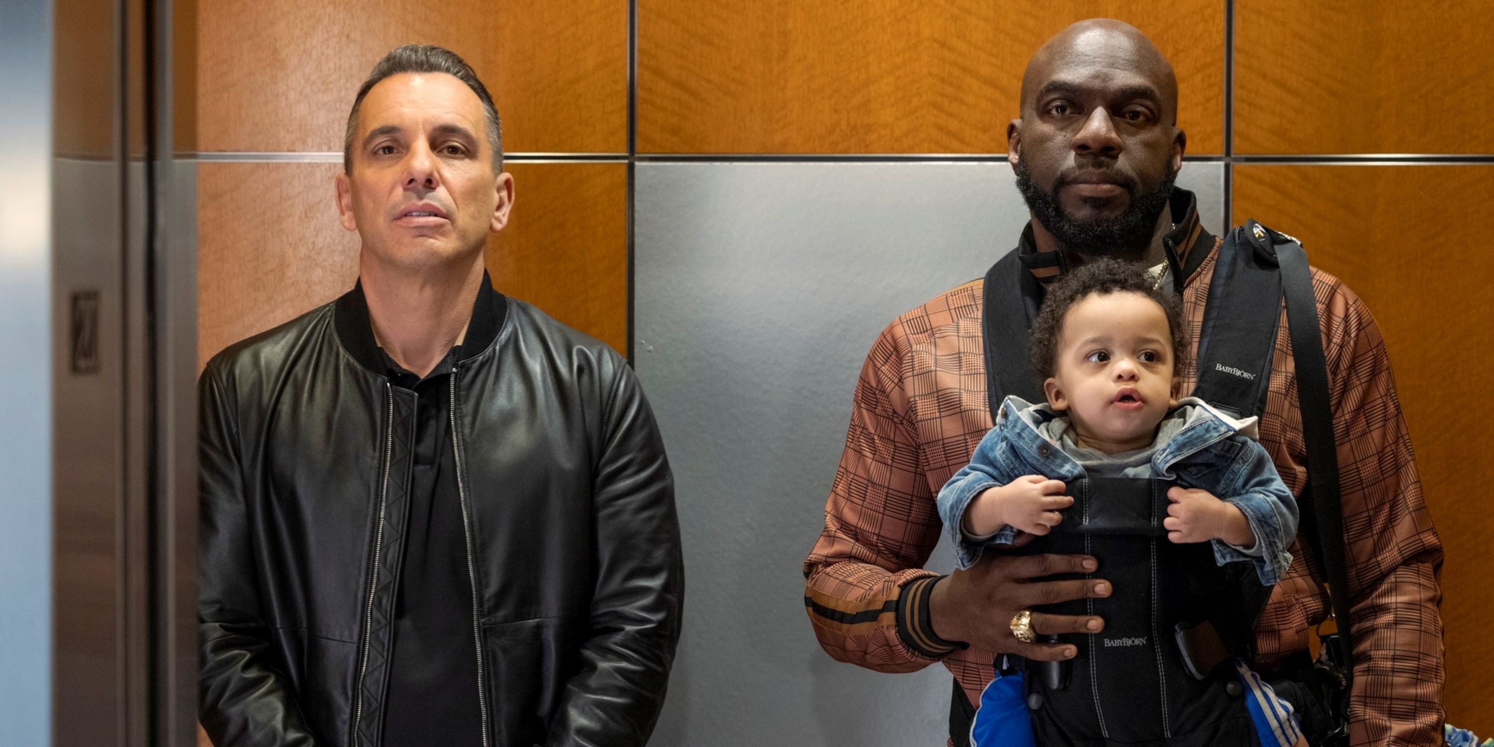 Sebastian Maniscalco as Danny in an elevator next to Omar J. Dorsey as Ray with a baby in Season 2 of Bookie