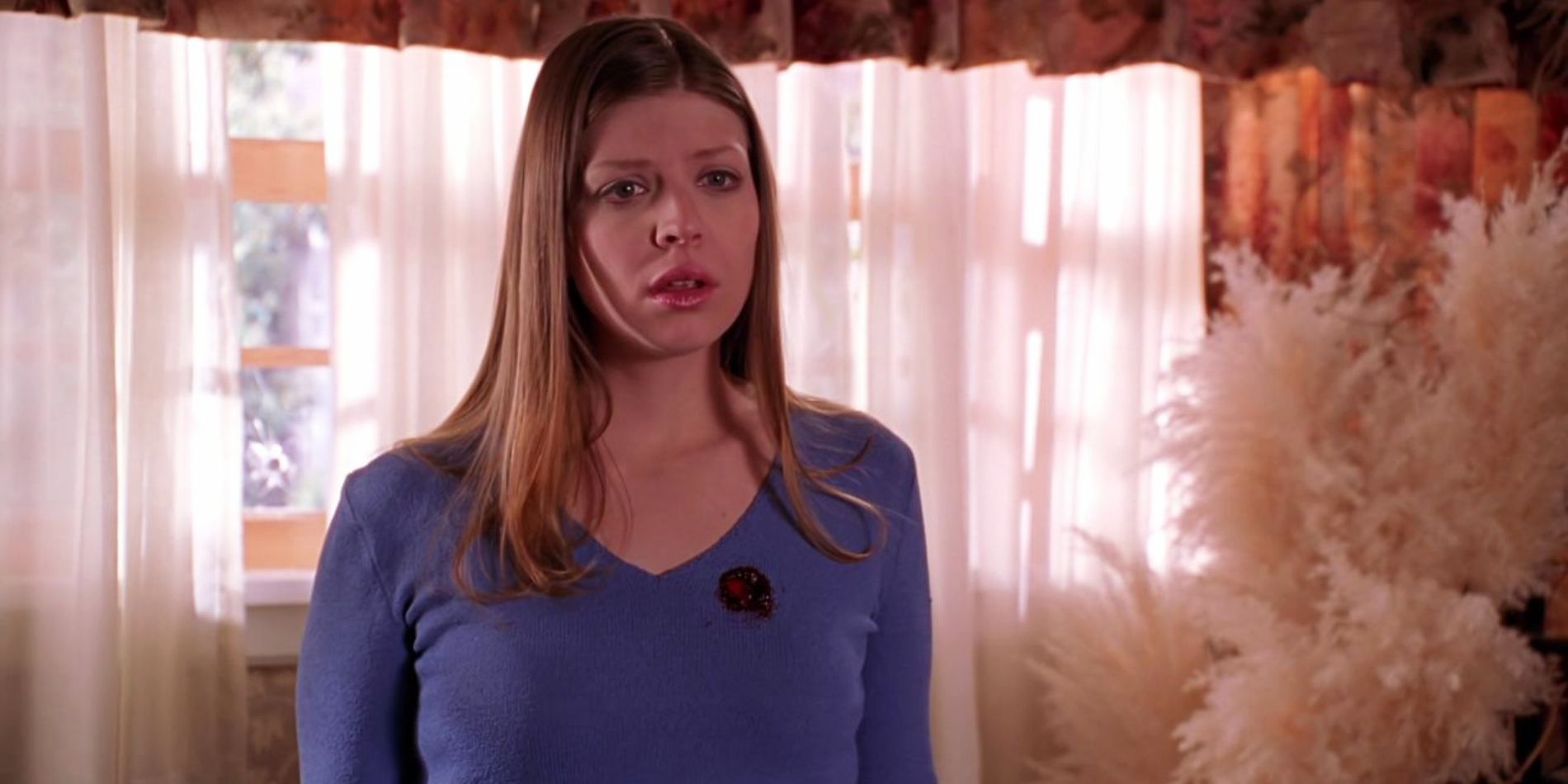 Amber Benson as Tara Maclay looks confused with a spot of blood on her chest in Buffy The Vampire Slayer.