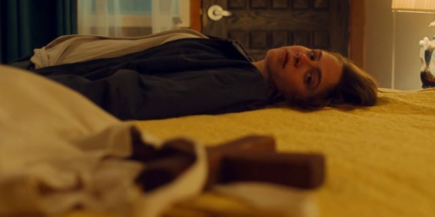 Remy, portrayed by Olivia Luccardi, lies on her motel bed while looking at her cross.