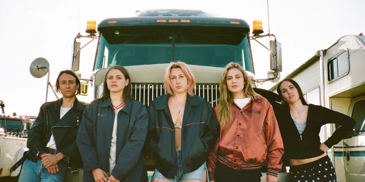 The cast of Candy Land poses in front of a semi-truck. 