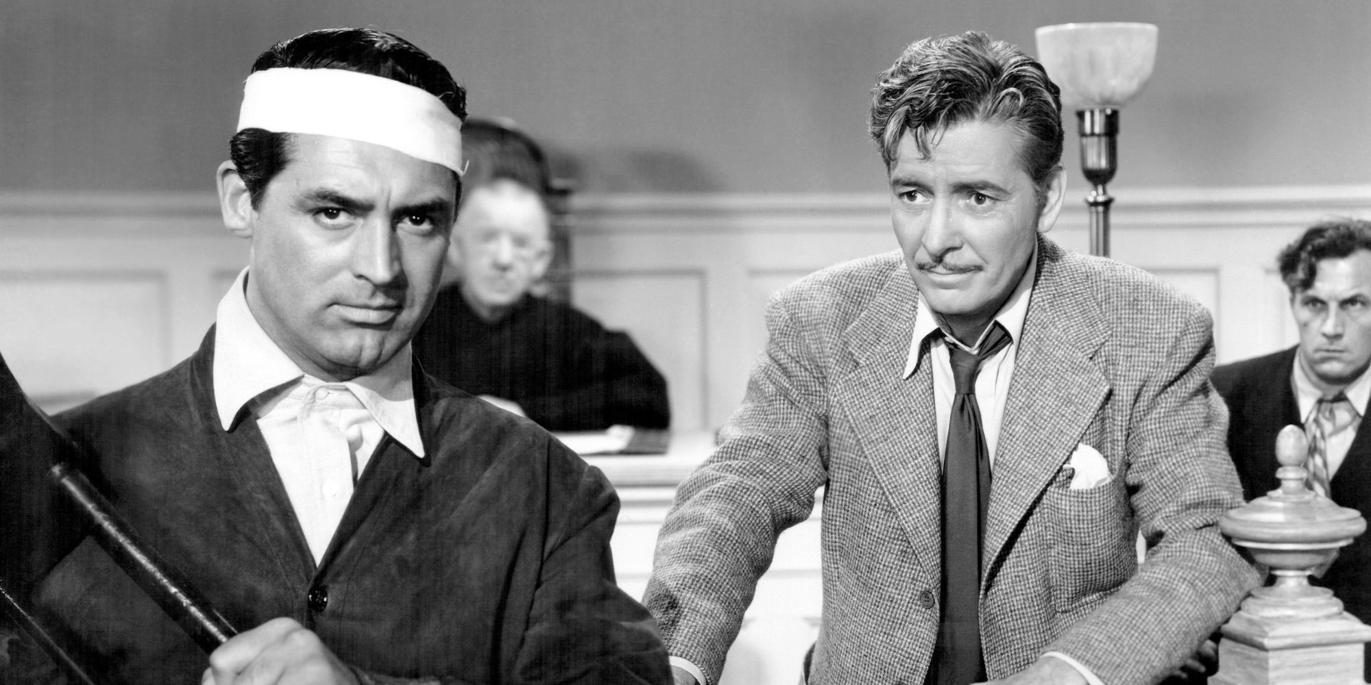 Cary Grant holding a chair up in front of himself and Ronald Colman standing behind him inThe Talk of the Town (1942)