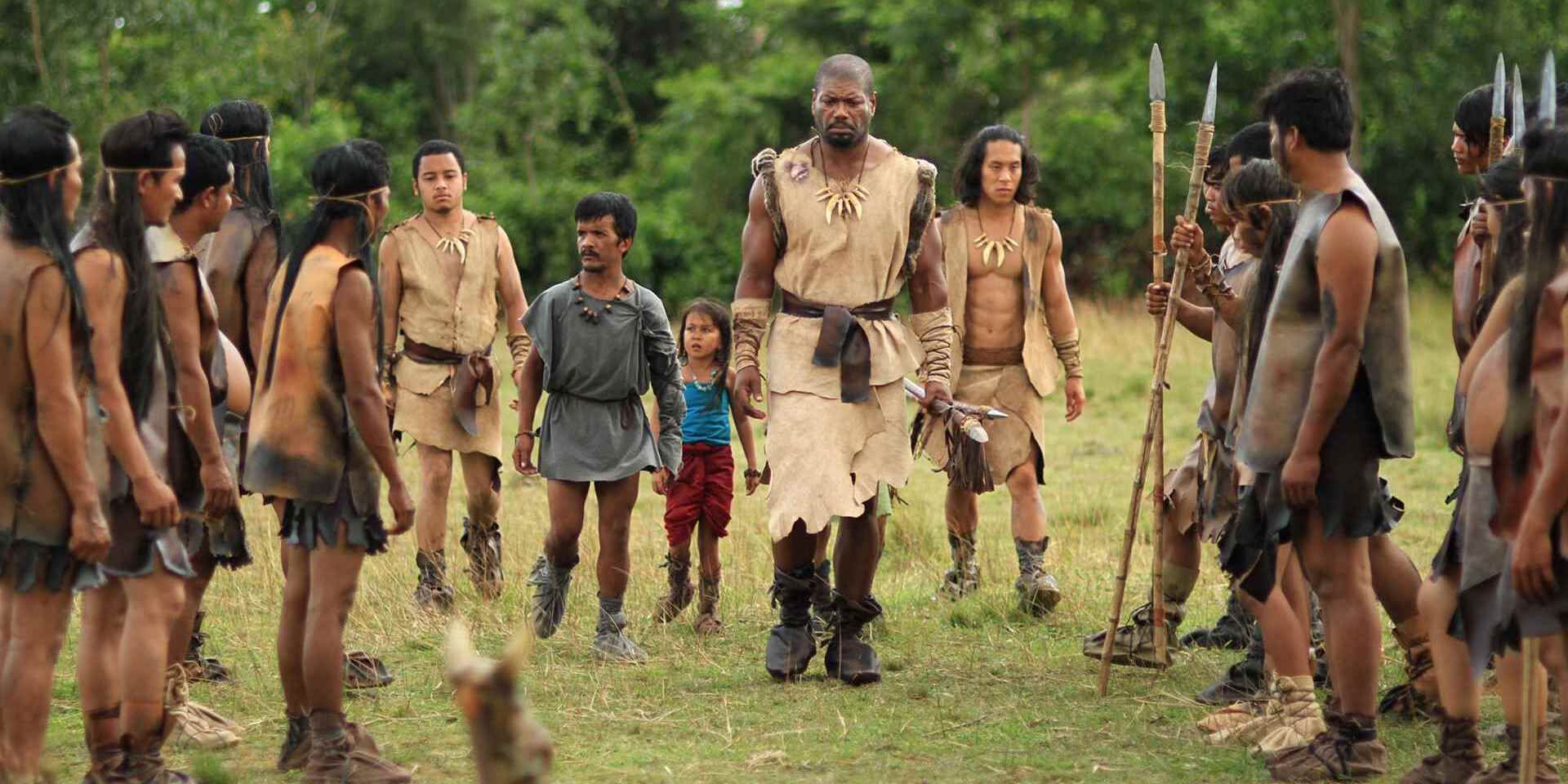 A man wearing tan cloth walking somberly through a group of warriors holding spears in &lsquo;Clash of the Empires&rsquo;