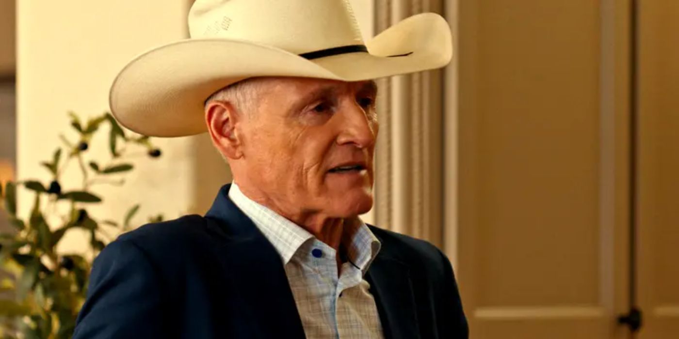 Colm Feore as Nathan in a suit and cowboy hat sits and talks to someone off-camera in Landman.