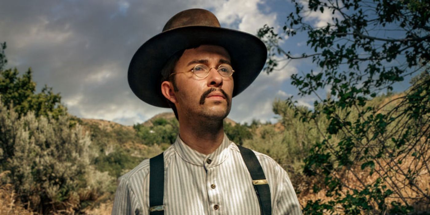 Mason Beals as Teddy Roosevelt, standing in the forest and looking at something off camera in Elkhorn.