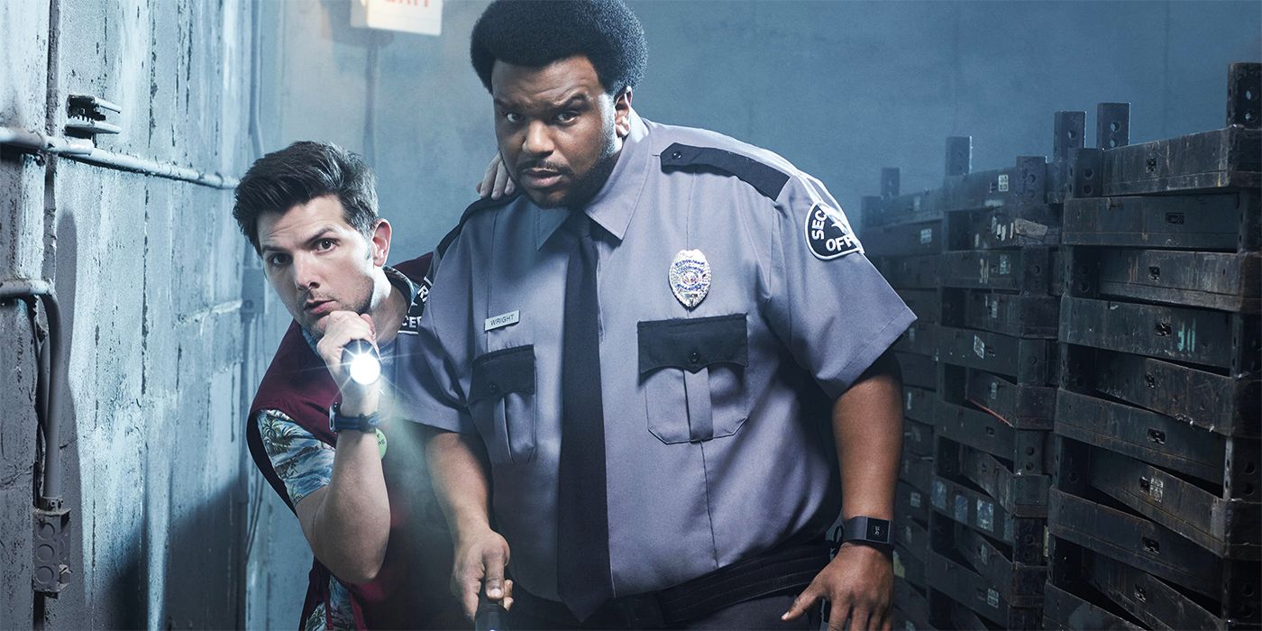 Adam Scott and Craig Robinson holding flashlights and walking down an alley looking at something in Ghosted