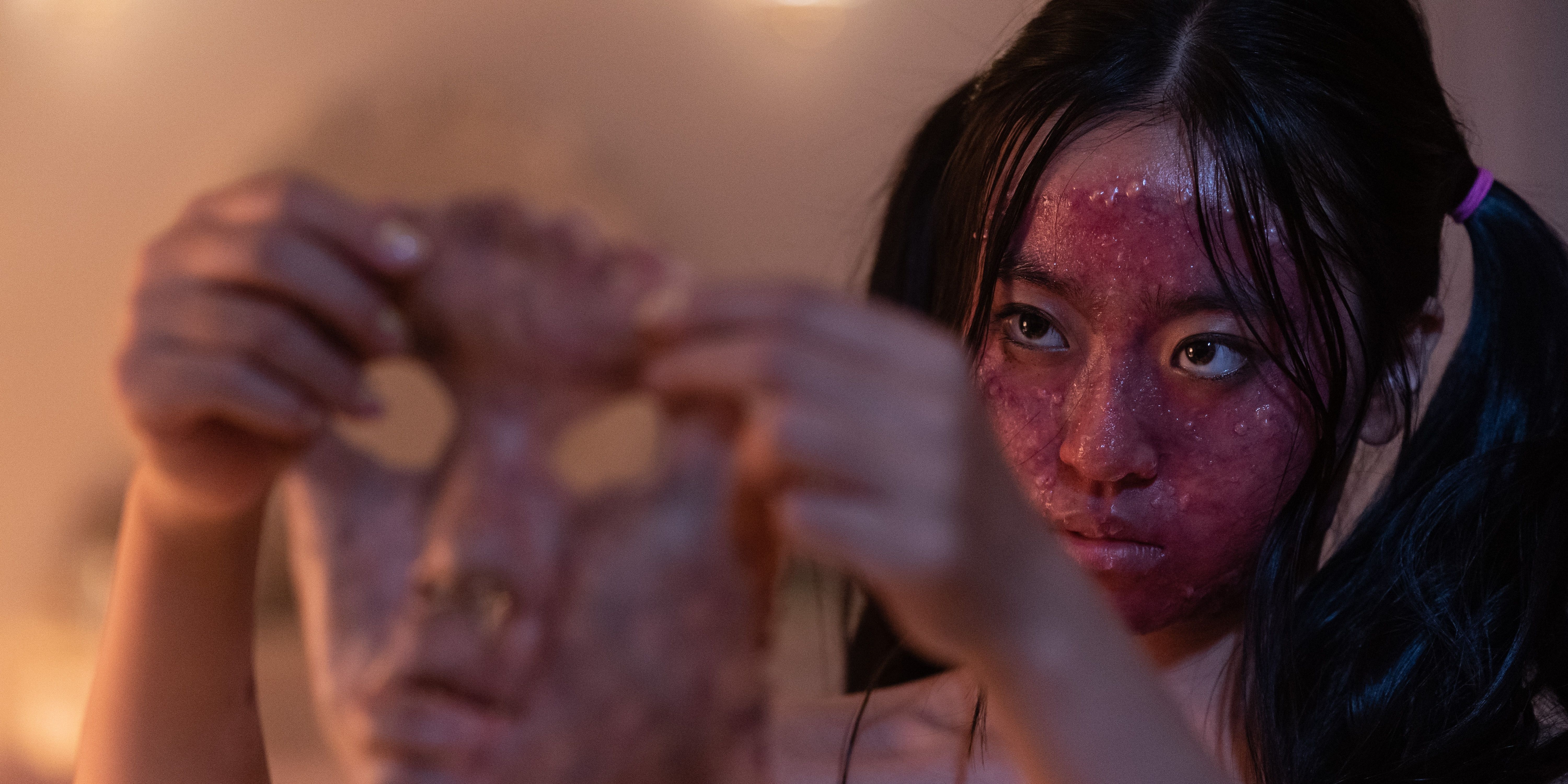 Joyena Sun as Wei holding another face to her own in Grafted