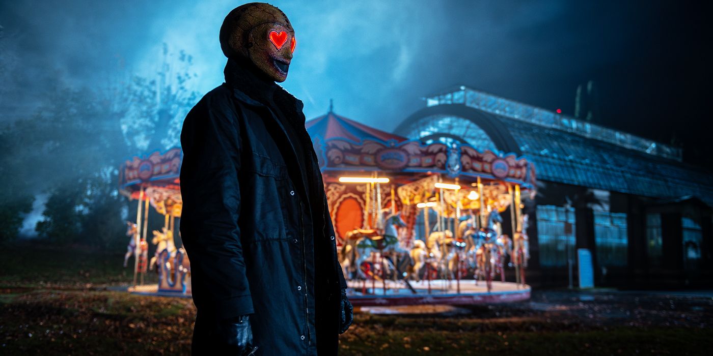 The Heart Eyes Killer outside at night in front of a lit merry-go-round