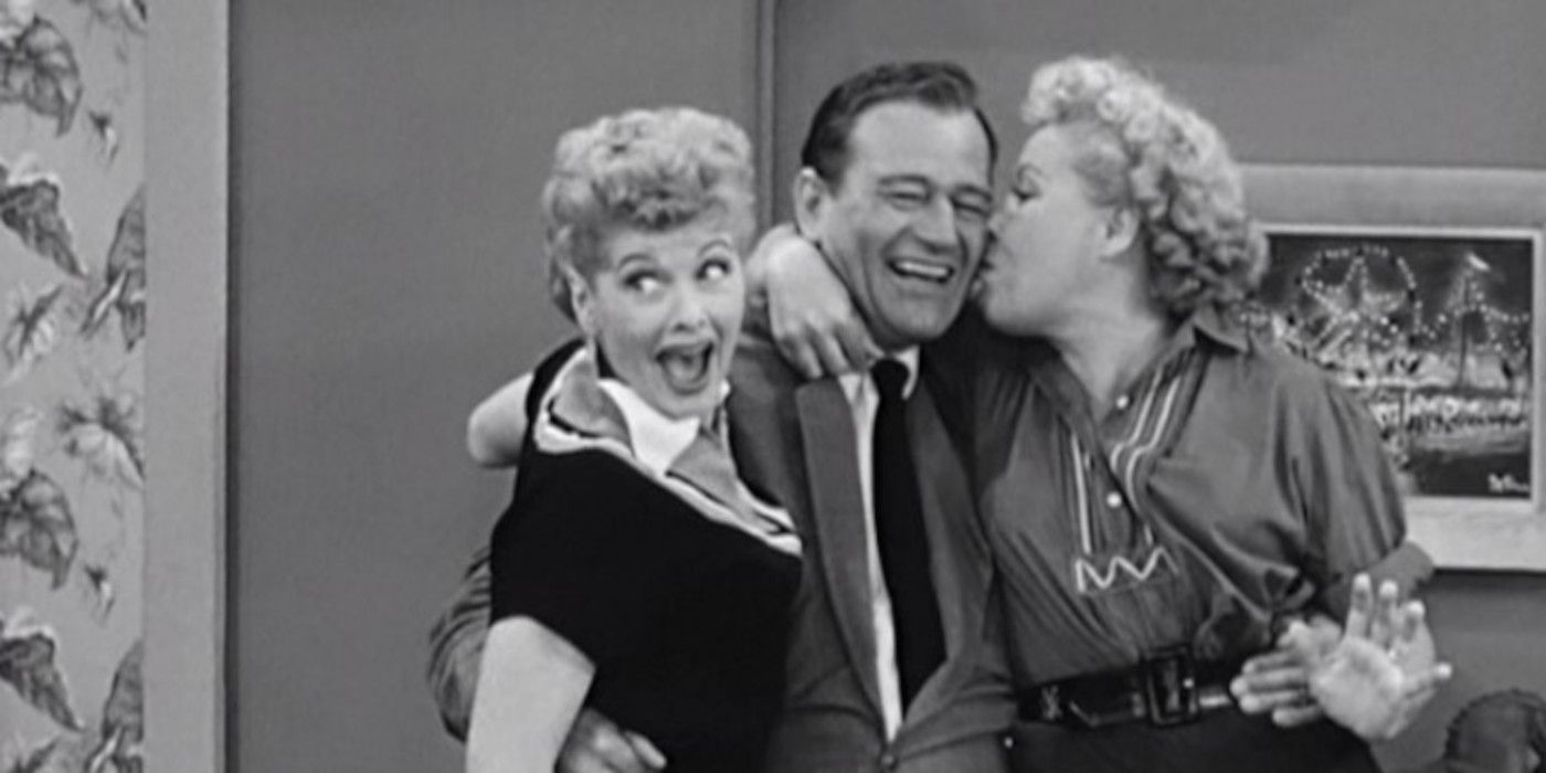 Lucy and Ethel hug a smiling John Wayne in I Love Lucy.