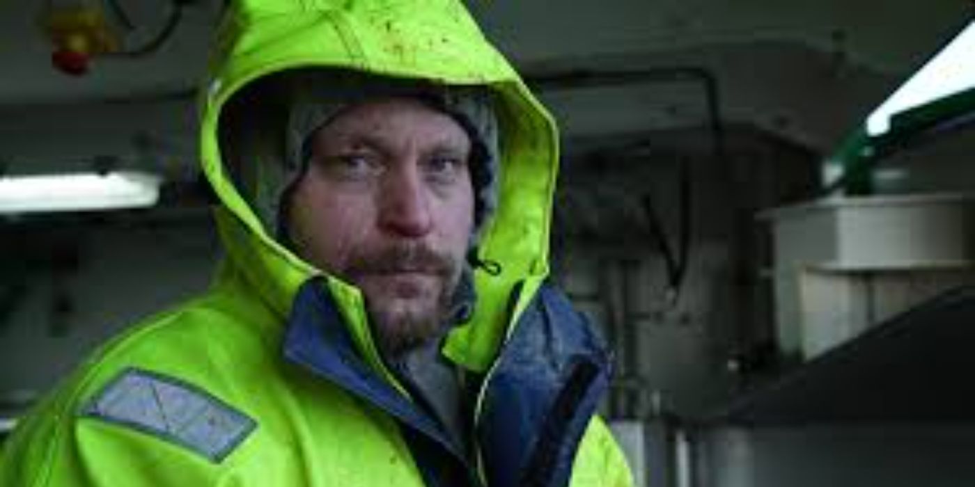 Once of the captains bundled up in a jacket inside the cabin of his ship in Ice Cold Catch.