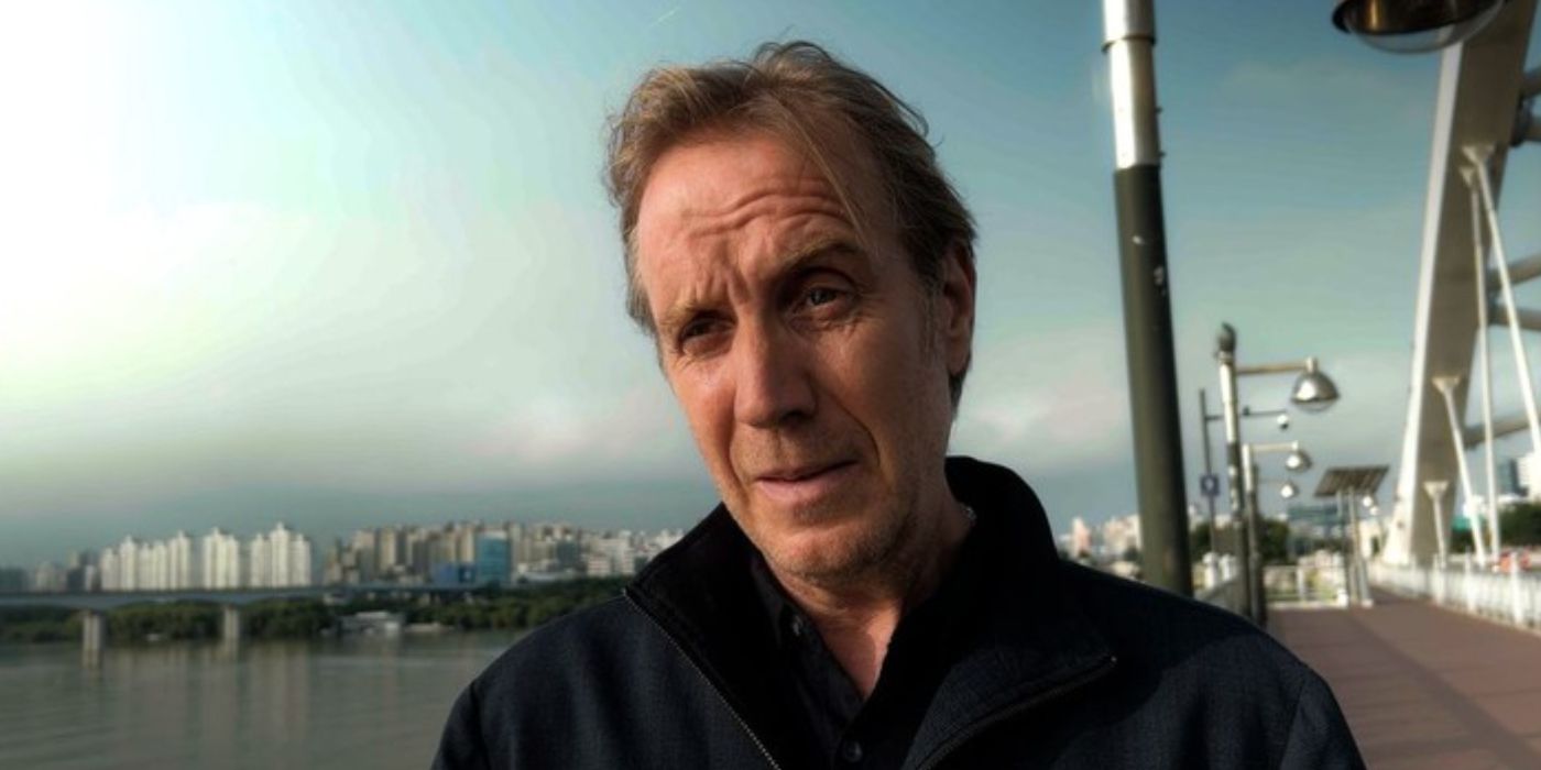 Close up of Rhys Ifans as Sam, standing on a bridge and looking serious in Inheritance