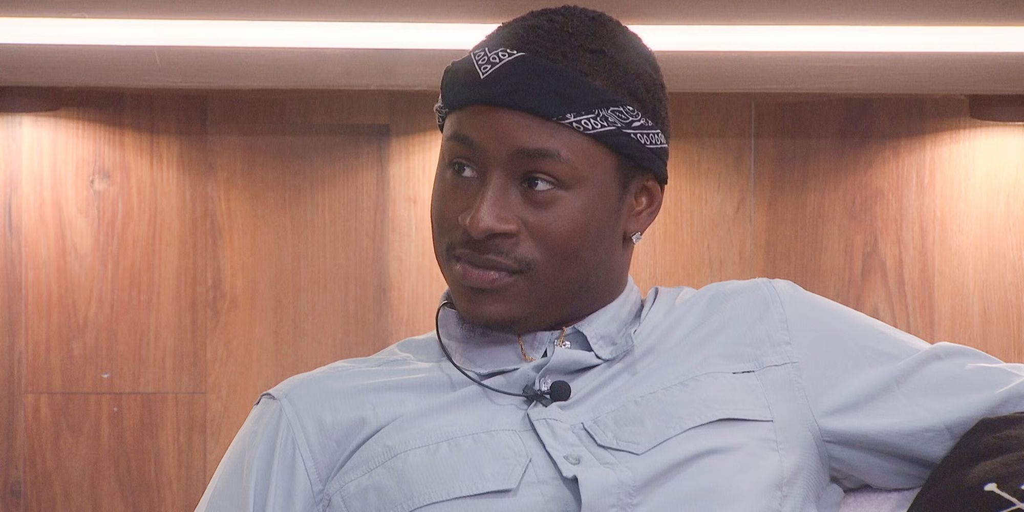 Jared Fields with a microphone around his neck, sits in the living room on Big Brother 25.