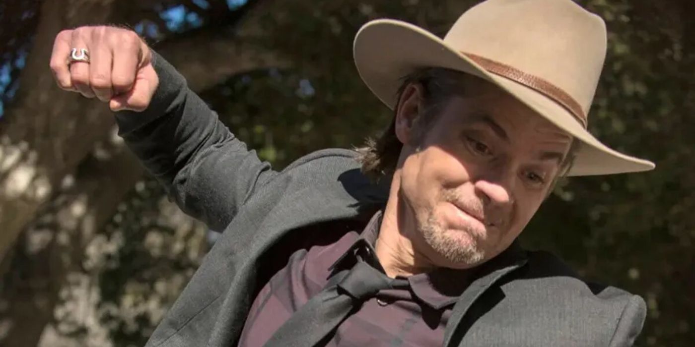 Timothy Olyphant as Raylan Givens looks angry with his fist in the air, about to punch someone in Justified.