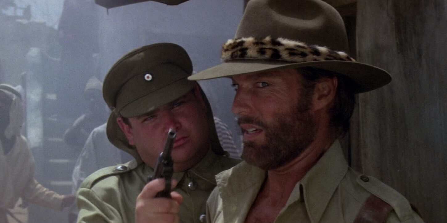 A solider holding a revolver up to a man in a safari outfit's face in 'King Solomon's Mines' (1985)