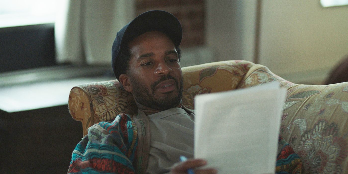 Roger (Andre Holland) reading papers while laying on a couch in Love, Brooklyn