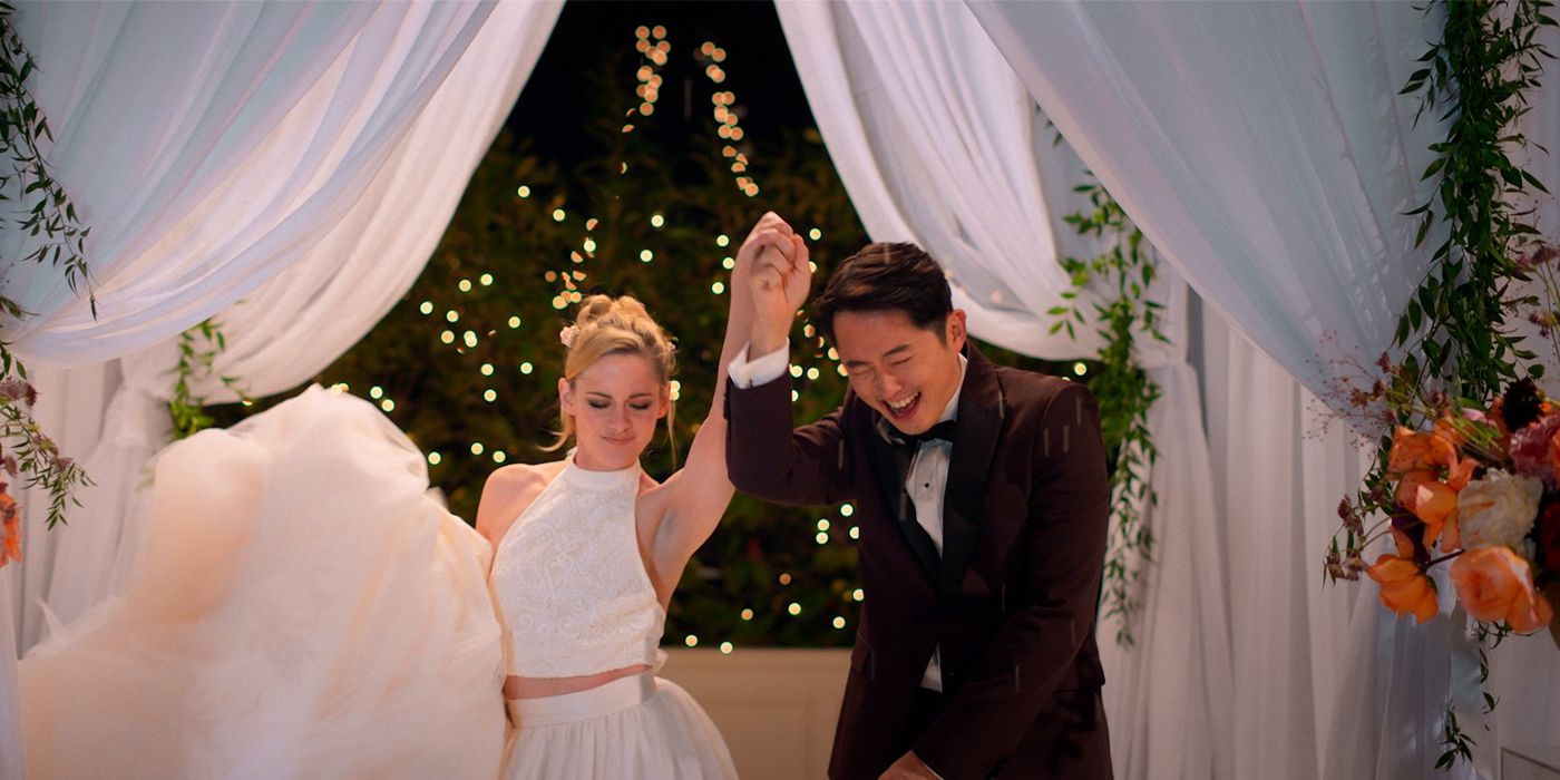 Me/Deja (Kristen Stewart) holding up Iam/Liam's (Steven Yeun) hand at their wedding in Love Me