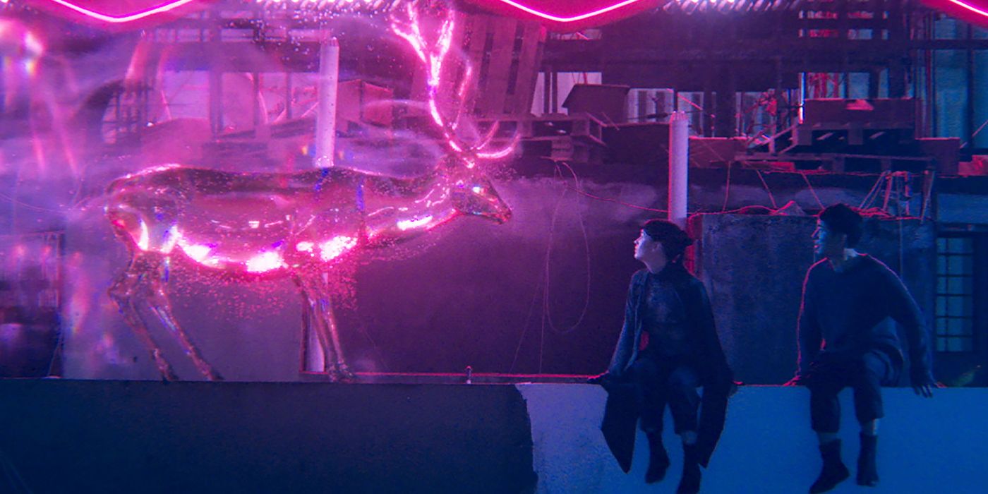 Ren (Sandrine Pinna) and Wei (Xiaodong Guo) sitting on a ledge looking at a pink luminescent deer in Luz
