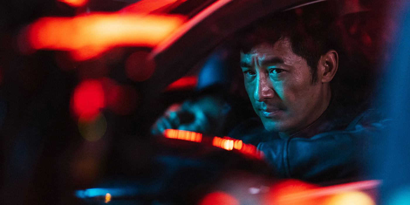 Wei (Xiaodong Guo) in a car illuminated by orange lights in Luz